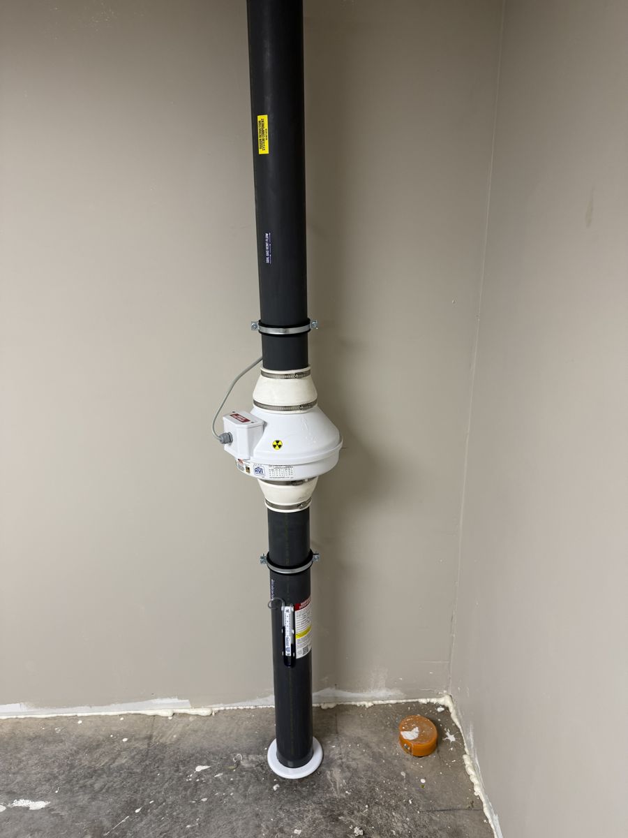 Radon fan and pipe installed in a finished basement corner