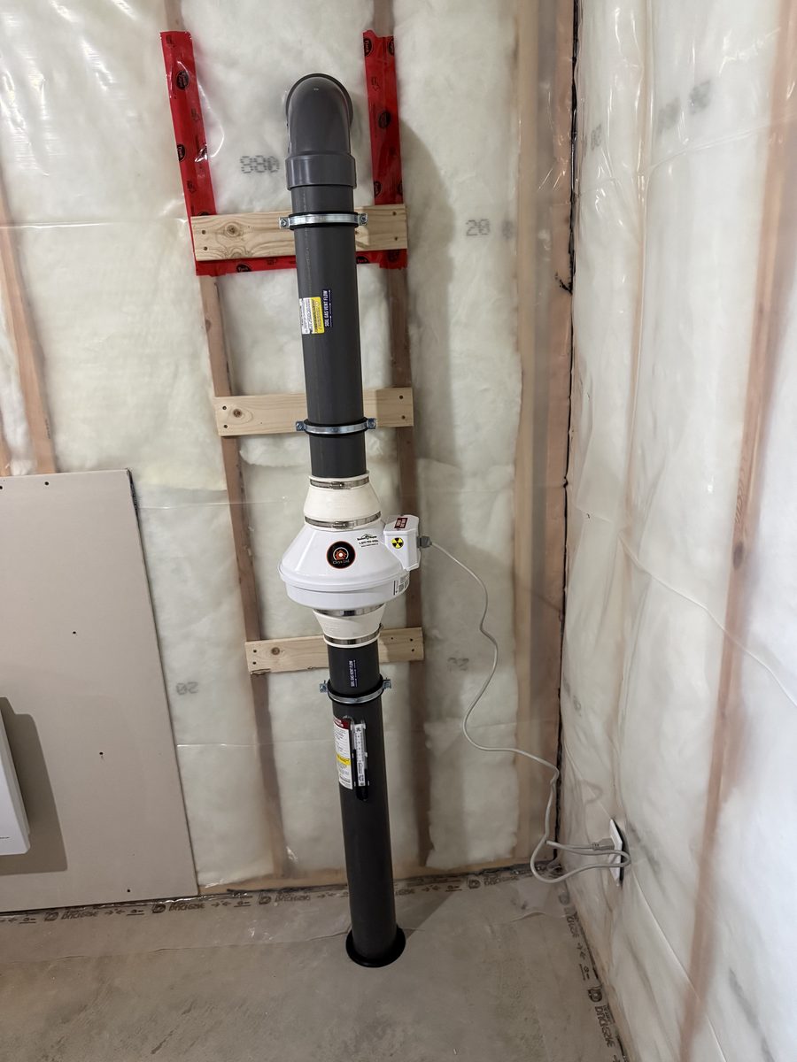 Radon fan and pipe installed on a framed wall in a new home basement before drywall